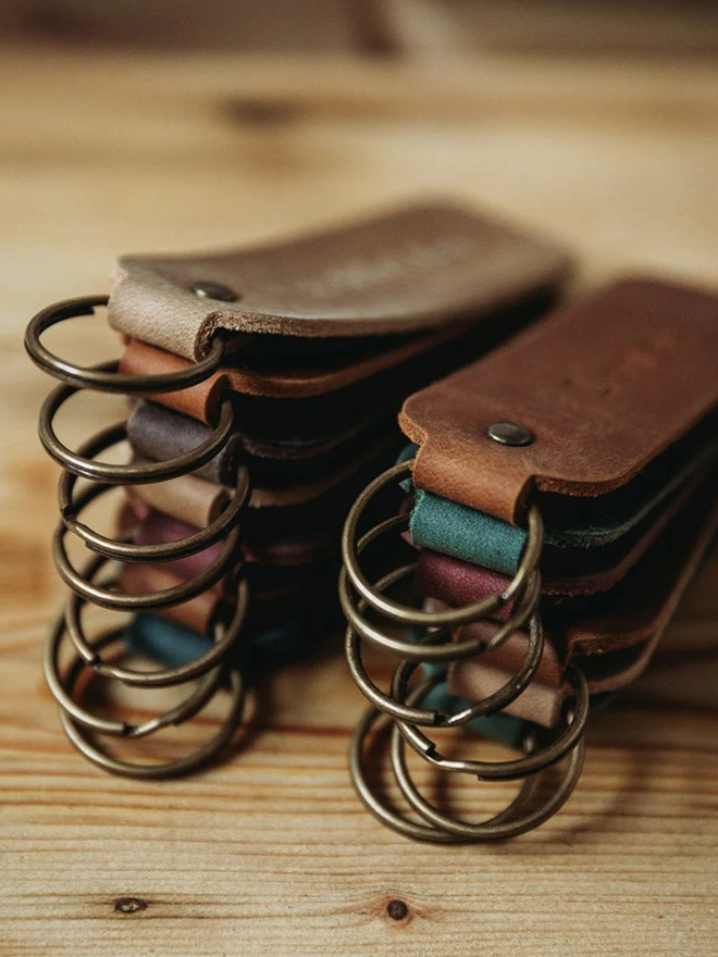 encouraging leather keyring. a stack of leather keyrings in various colours, atop a wooden table.