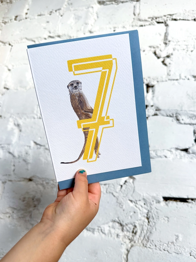 white card with a big yellow number 7 and an illustrated meerkat with a blue envelope