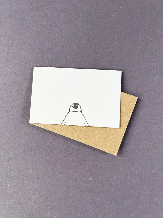 Letterpress flat tiny note printed with a baby penguin at the bottom