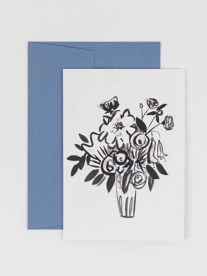 A greetings card featuring a blank line illustration. Photographed with a pale blue envelope of a vase of roses and foliage
