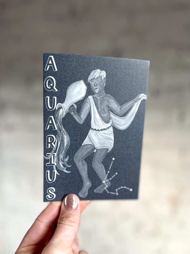 a greetings card featuring a greyscale illustration of a zodiac style water bearer with the text “AQUARIUS”