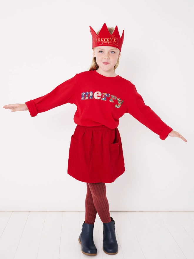 a 5 year old wearing a red christmas cotton t-shirt with the word merry hand cut from festive Liberty prints and appliquéd on the front