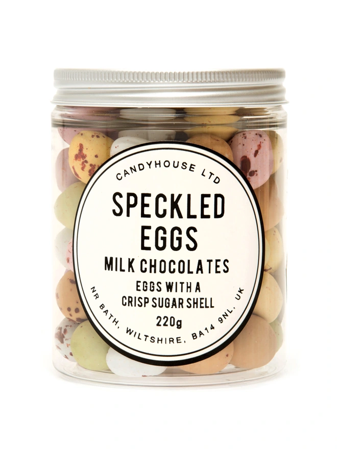 A clear jar of milk chocolate speckled eggs with a crisp sugar shell 