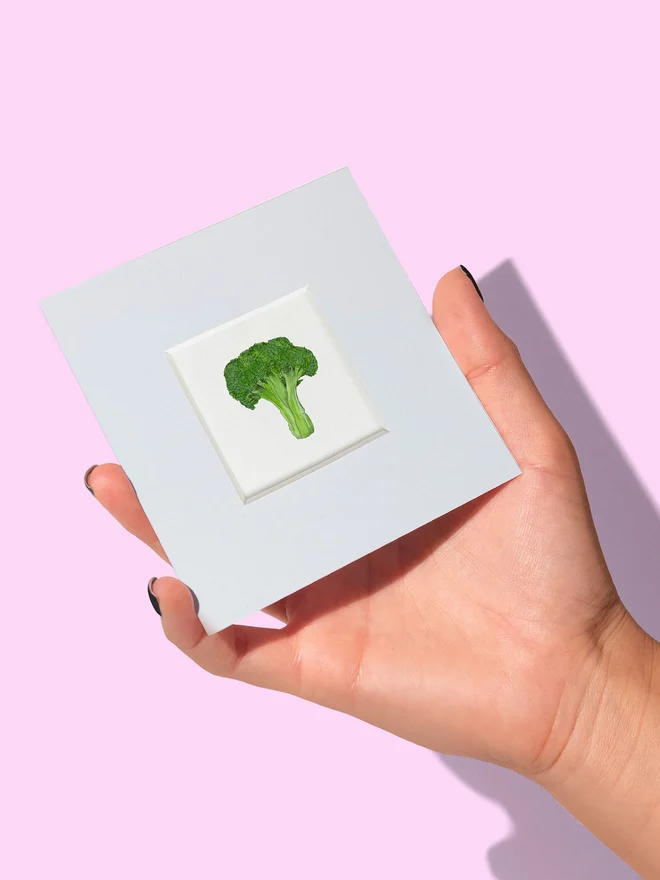 Hand holding a Broccoli tiny print with mount showing the size of the mini print 