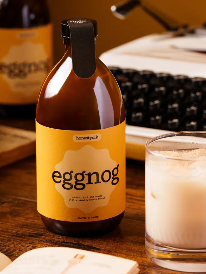 a glass of eggnog next to the bottle