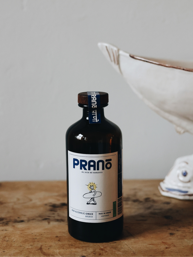 Dark brown bottle with white label sitting on a brown countertop with white background 