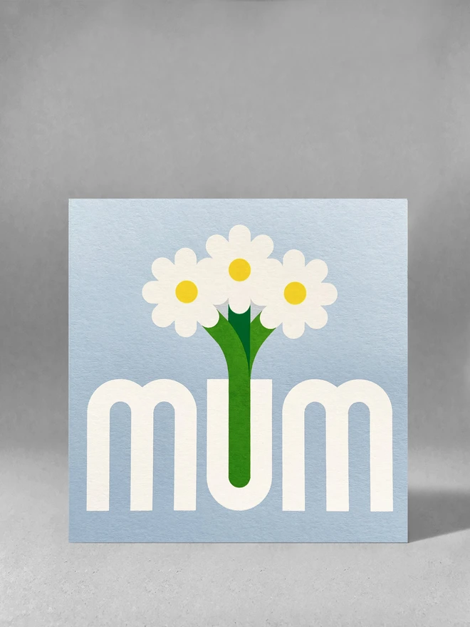 light blue square card with mum printed in grey, the U is a vase with three flowers stood in it. Card is stood in a light grey space with soft grey shadows.