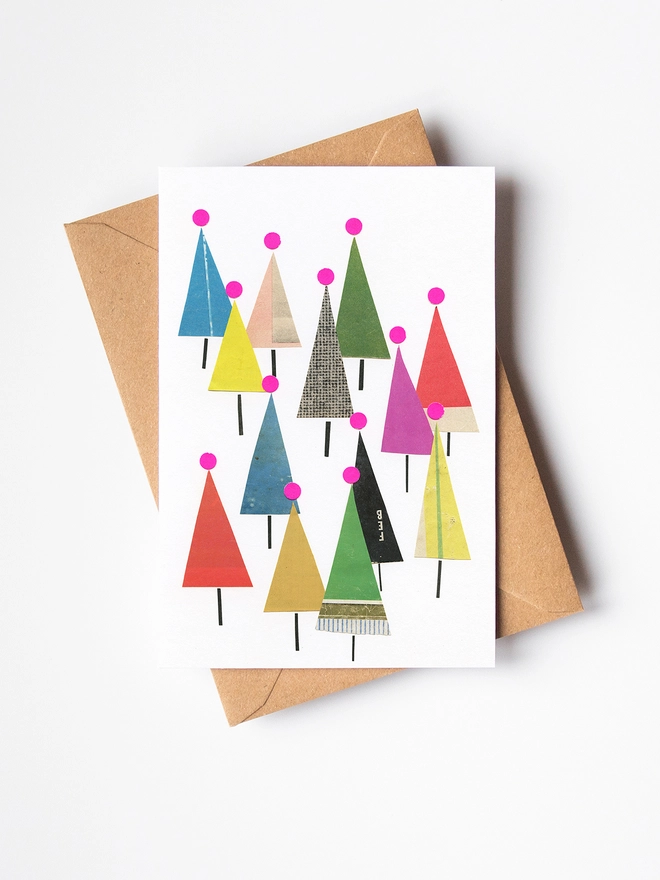A bright Christmas card depicting a forest of colourful fir trees.