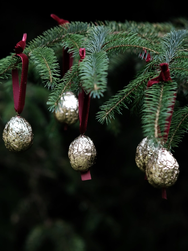 Handmade walnut Christmas ornament with delicate gold gilding, showing the natural shape and grain of the wood. A traditional, nostalgic Christmas tree decoration with timeless old-fashioned charm.