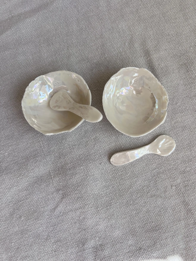 pair of porcelain salt and pepper dishes with matching spoons in pearl lustre