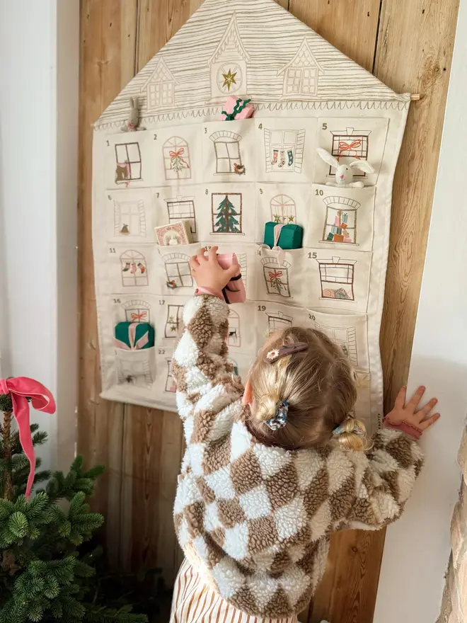 Fabric Christmas House Advent Calendar, with a little girl putting in a present. 