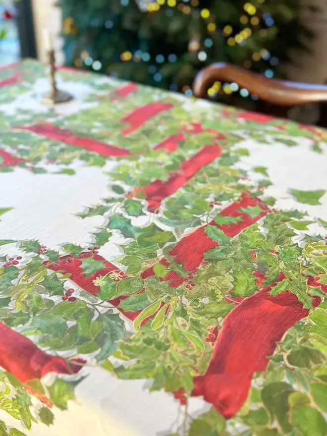 christmas garland lattice tablecloth. a tablecloth printed with holly, ivy and mistletoe on a table.