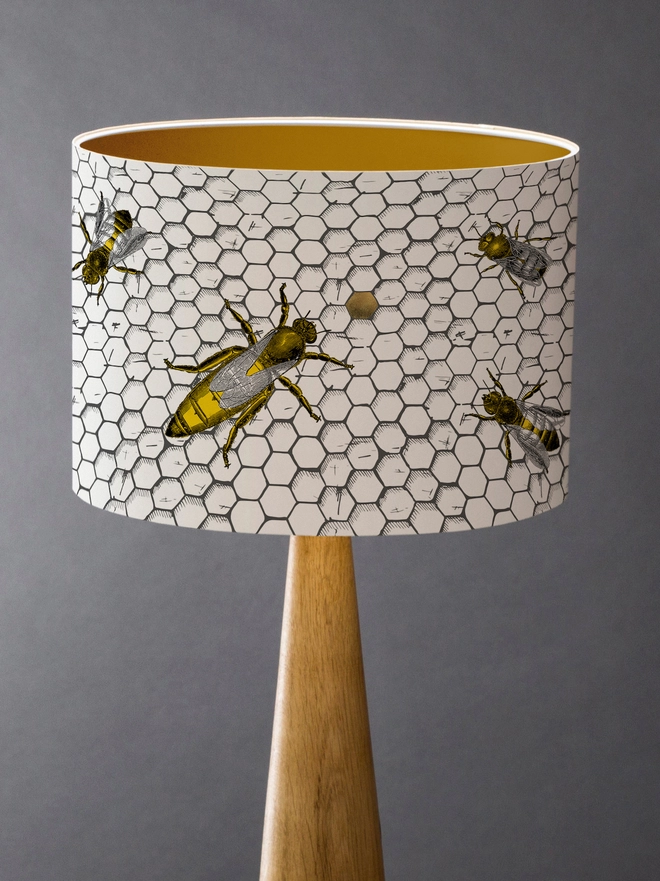 Drum Lampshade featuring honey bees on a honeycomb with a gold inner on a wooden 