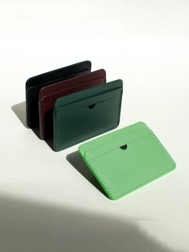 Cardholders laid at an angle with the sea green, dark green, and black laid out. With the sea green at the closest to camera
