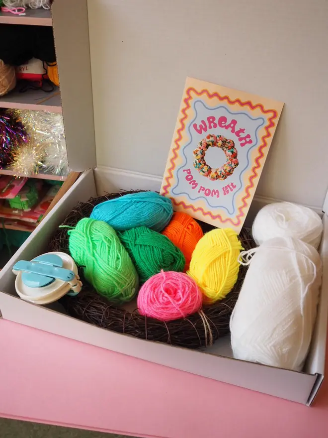 Inside the Floral Wreath Kit is a range of bright coloured yarns, a pom pom maker, a wreath base and instructions
