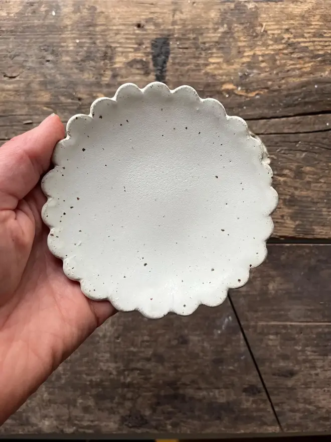 Handmade Scalloped Ceramic Dish, a ceramic dish sitting above a wooden surface. 