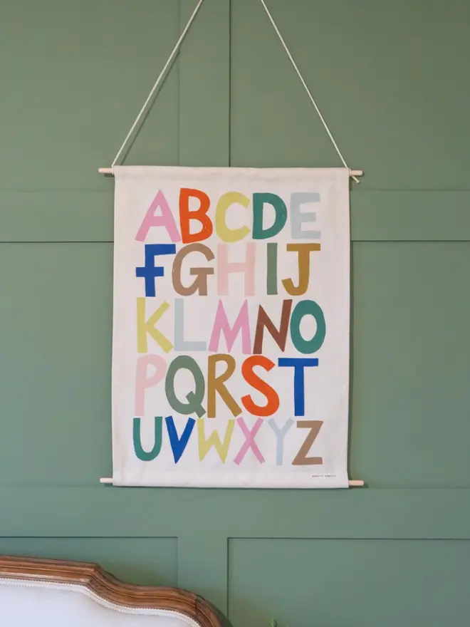 Rainbow Alphabet Fabric Banner, hanging on a green wall. 