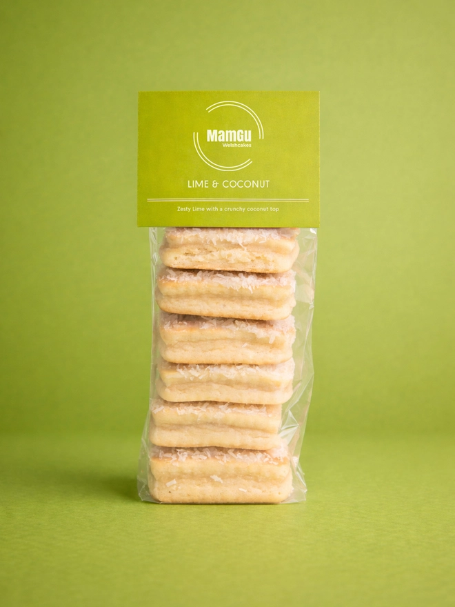 Lime and Coconut Welsh Cakes stacked with a green MamGu Welshcakes label on top and a green background