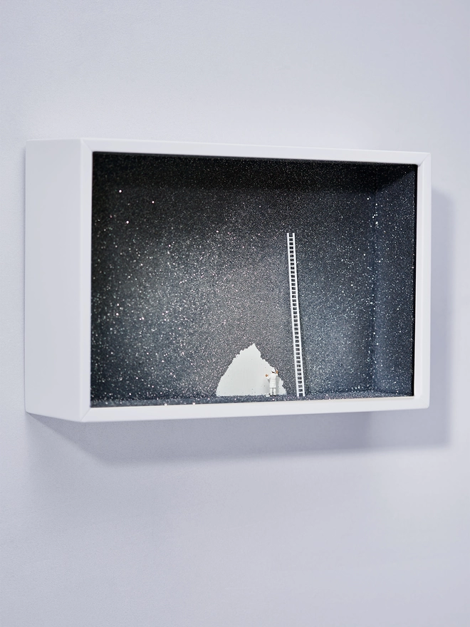 Miniature scene in an artbox showing a tiny painter figurine painting the night sky sparkling black and silver 