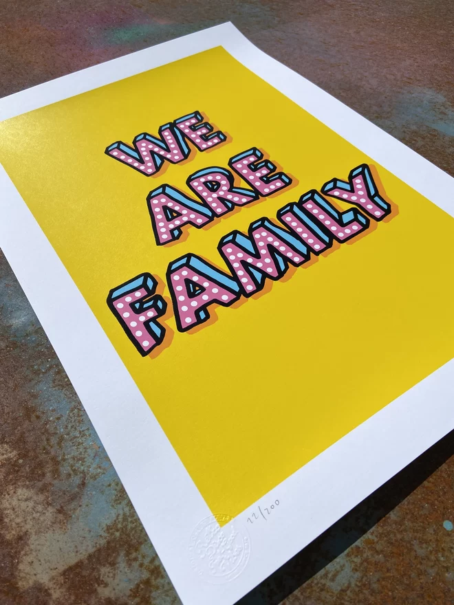 Portrait "We Are Family" Hand Pulled Screen Print with yellow back ground and hand drawn letters that say “we are family” with an extra drop shadow in orange 