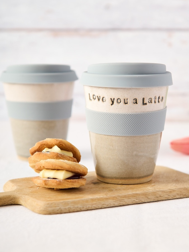 'soup' ceramic travel mug. a grey and white travel mug with light blue lid and band. 