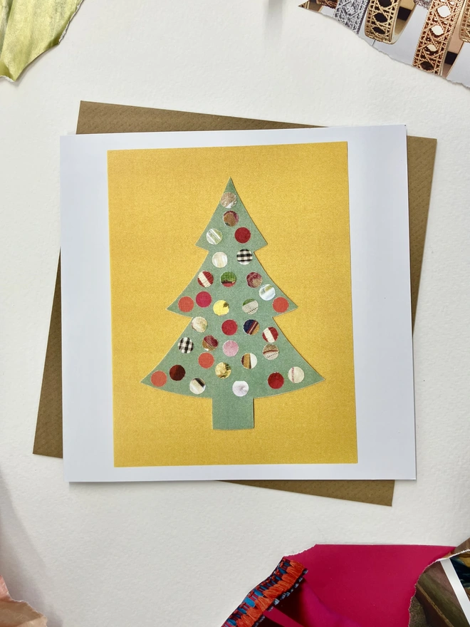 Christmas card featuring a sprinkle illustrations of a tree on a white background with collage papers