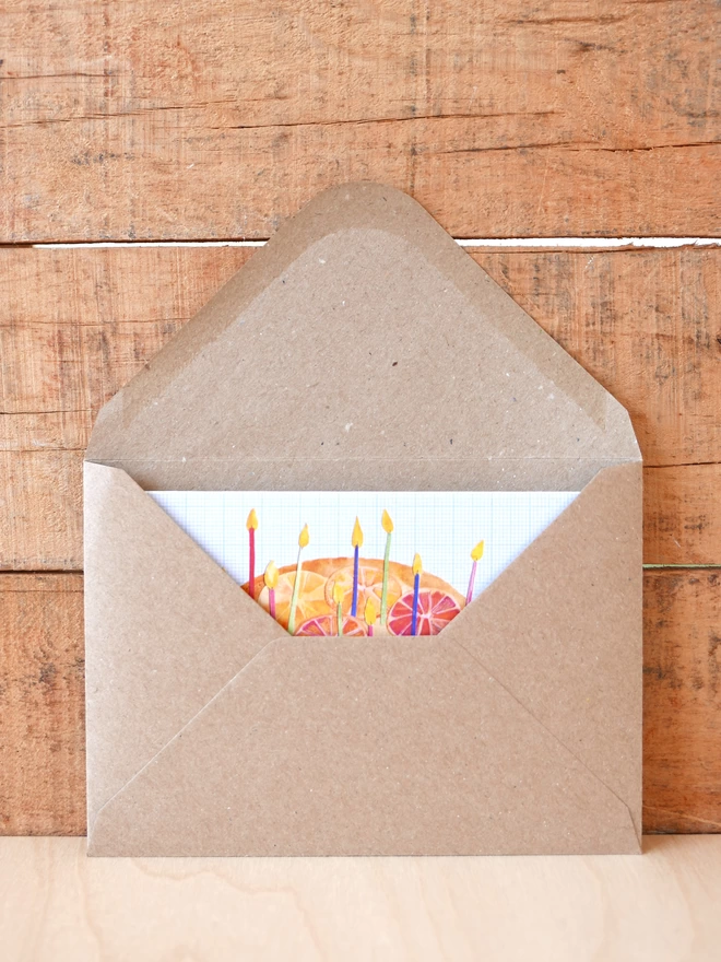 The Orange Upside Down Birthday Cake Card tucked inside its brown envelope with some card visible