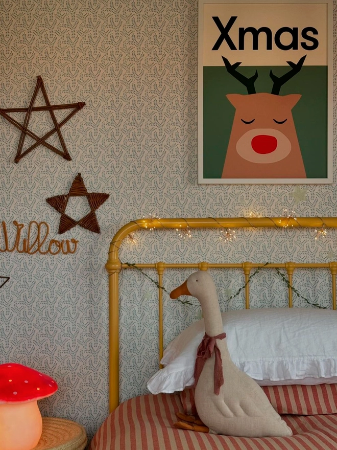 Bold illustrated reindeer wall print hanging in a childs bedroom above a bed