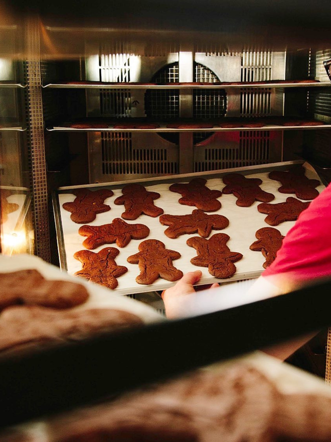 artisan chocolate orange gingerbread men on baking tray being placed into oven