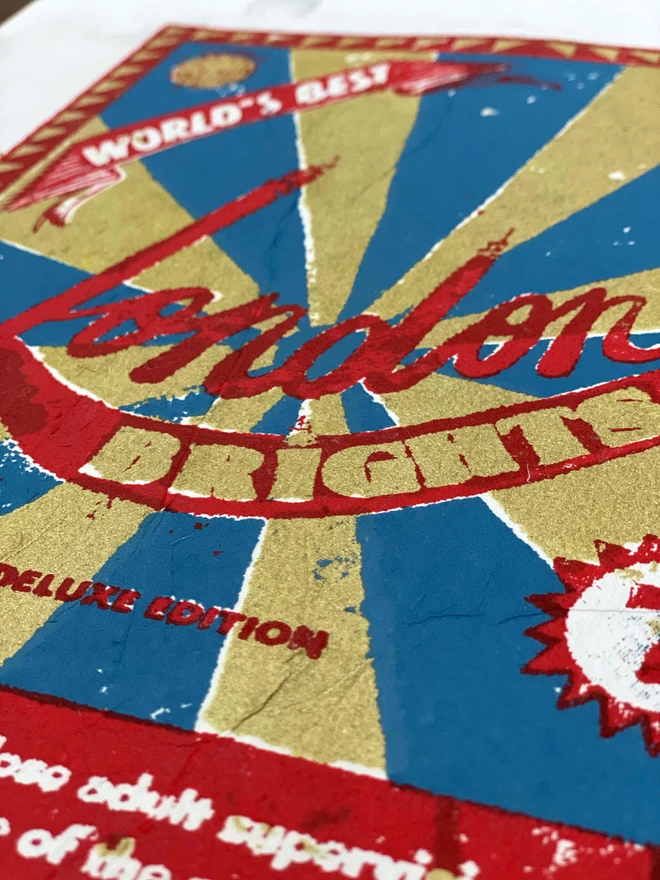 Bring a touch of nostalgic British charm to your space with this striking London Brights limited edition screen-print, inspired by the bold graphics of fireworks labels.     Featuring a vibrant palette of red, blue, and gold, the design showcases dramatic sunburst rays and retro typography, capturing the energy and character of classic mid-century advertising.      Each print includes the artist’s signature and edition number, this piece is perfect for lovers of London, vintage design, and unique statement art.