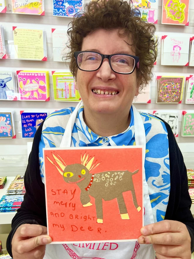 Artist holding a handmade riso printed Christmas Holiday greeting card with reindeer