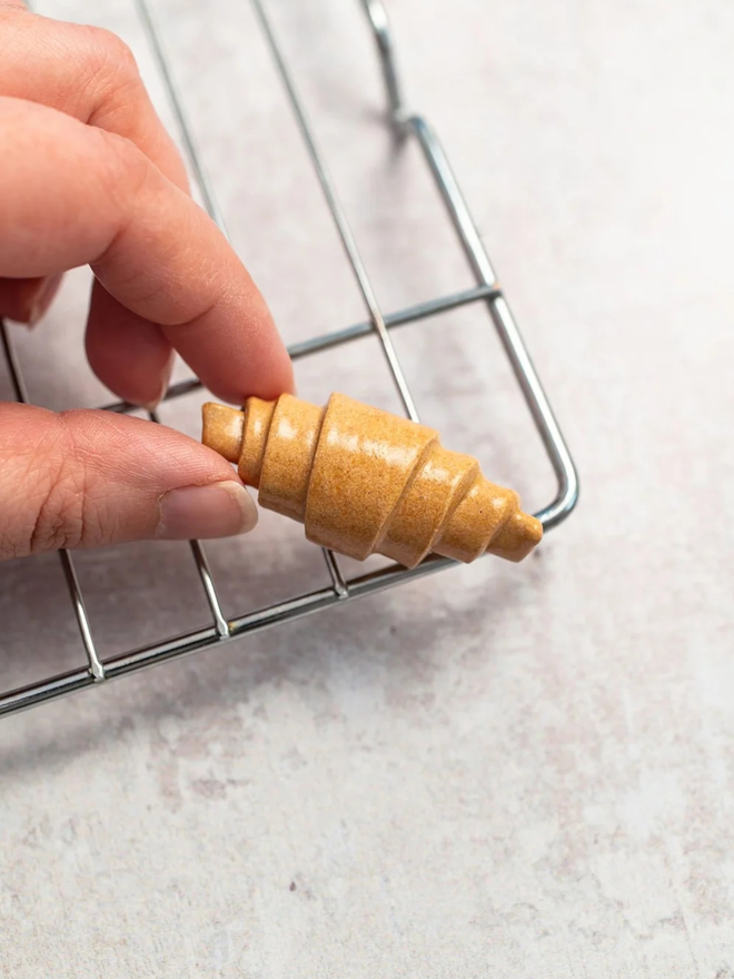 ceramic pastry pin badges. a ceramic croissant badge on a baking tray.