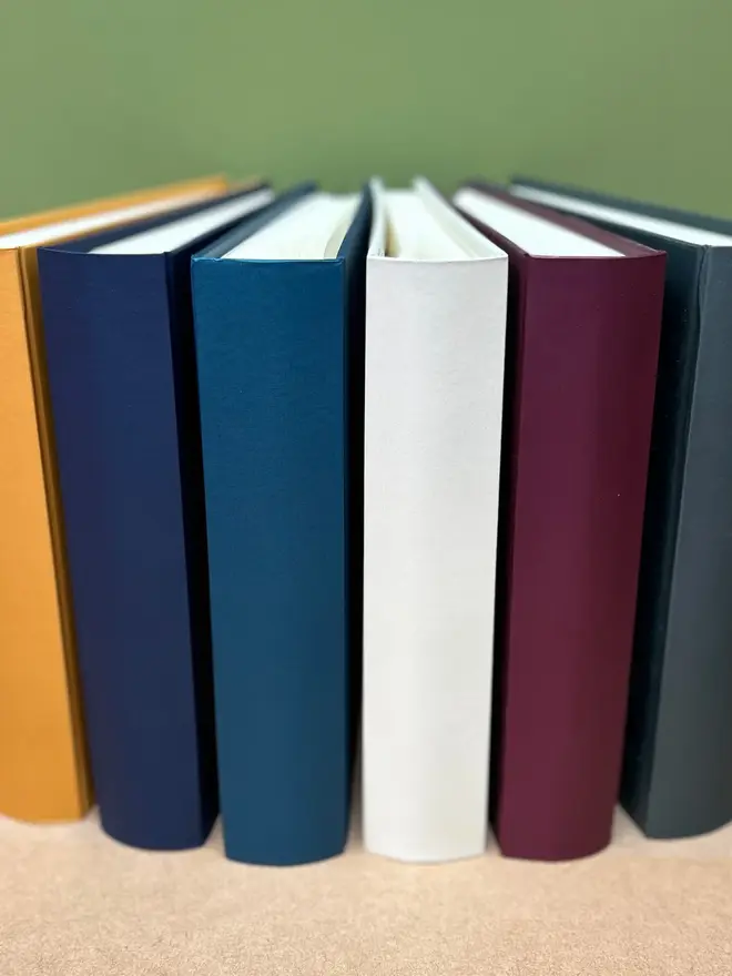 Personalised Large And Luxurious Family Photo Album, stack of photo albums on a wooden surface. 