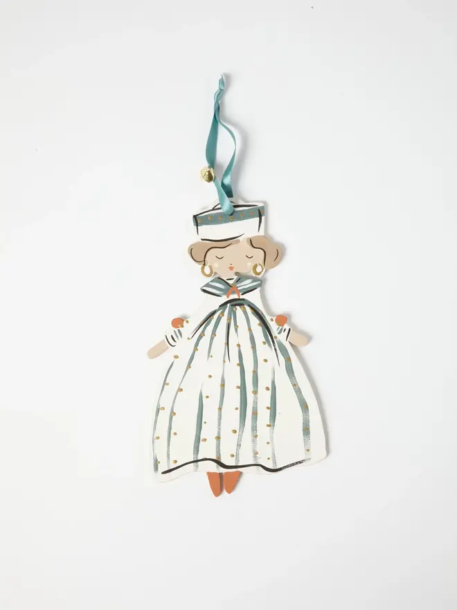 Sailor Queen Tree Dancer. a close-up flat lay shot of the sailor queen tree dancer hanging ornament on a plain white background, showing the figure's striped sailor hat, curled hair and gold hoop earrings in fine detail. her teal and cream striped gown is dotted with gold, with orange-toned shoes visible beneath the hem. she hangs from a teal ribbon with a small gold bell attached.