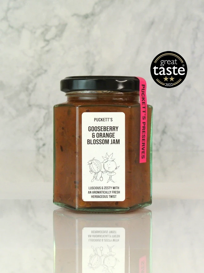 gooseberry and orange blossom jam. a jar of jam photographed on a marble background.