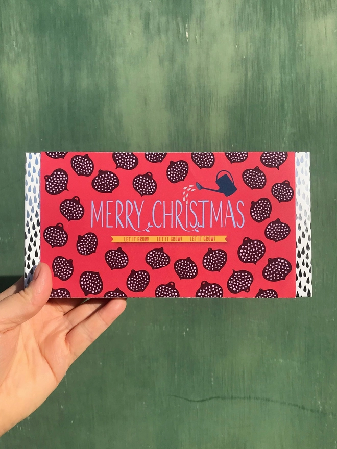 Growbar with a Merry Christmas gift wrap held against a green background. 