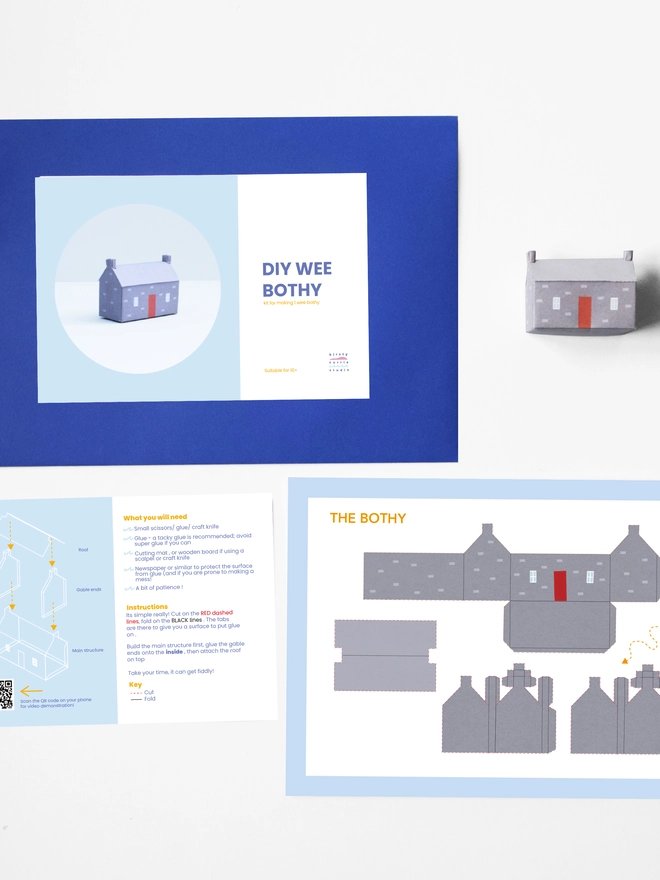 A photo of the elements of the DIY kits laid flat including - instructions, cut out sheet, a bothy made of a paper, an envelope with a label saying it is a DIY kit. 