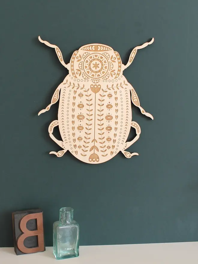 Folk Art Beetle Wall Hanging, wooden insect decoration hanging on a wall. 