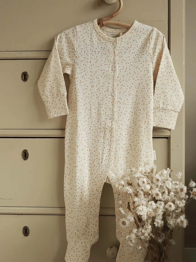 Printed Jersey Sleepsuit in Daisy Meadow hanging on a cabinet