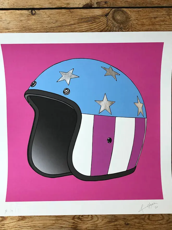 Motor cycle helmet with a star-and-stripe design on a pink background. 