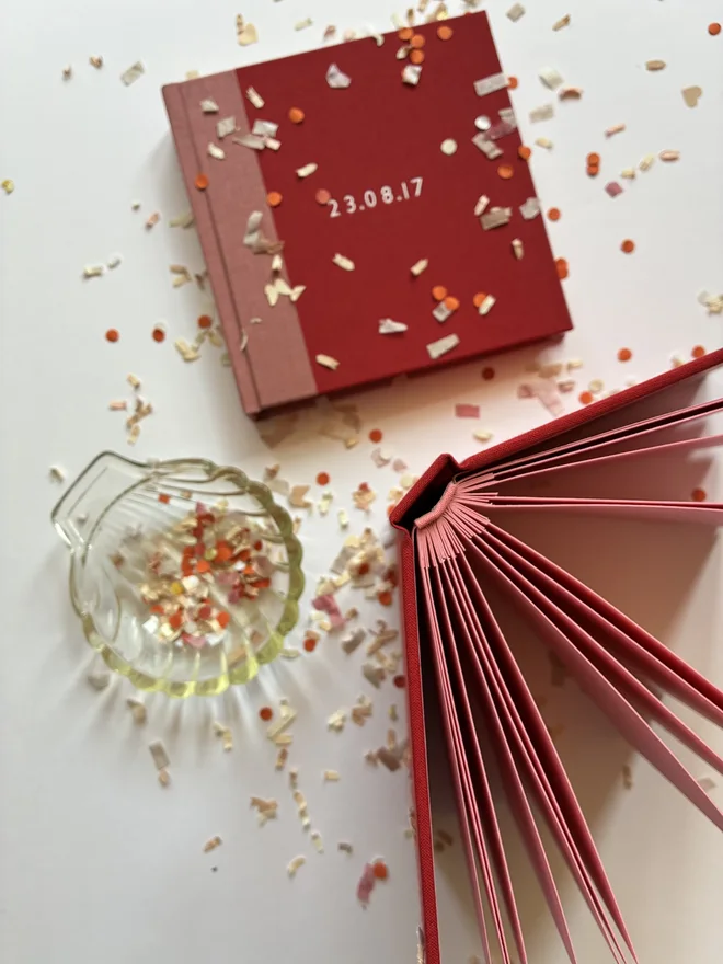 Two handmade instant photo guest book on a confetti littered table, one open and one closed