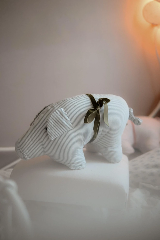 Cotton Pig Plushie, a cotton pig plushie sitting on a decorated bed. 