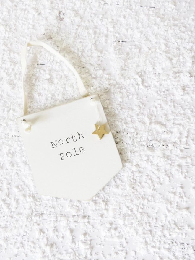 painted white banner with North Pole message strung with cotton and decorated with a wooden gold star.