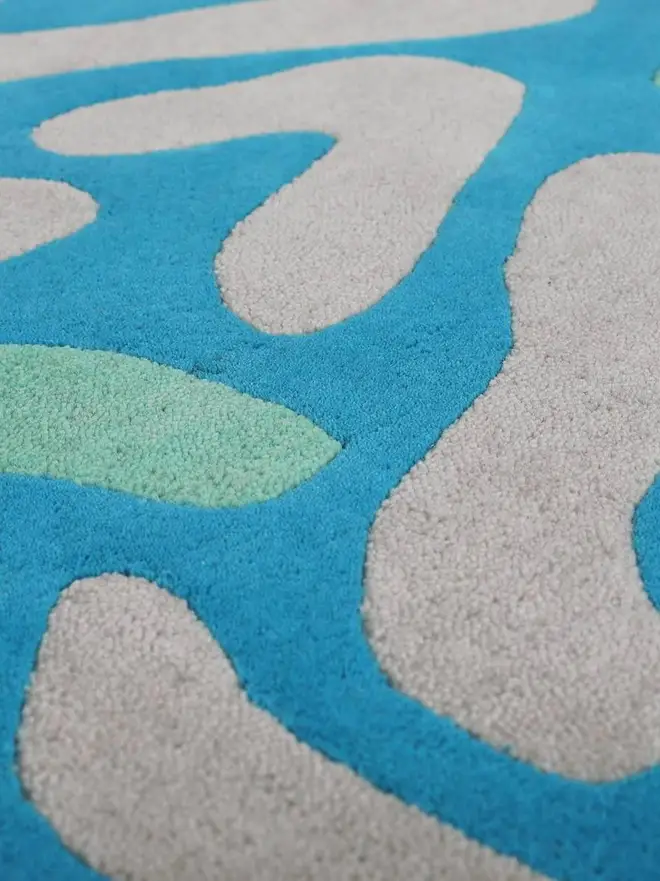 Lagoon Hand Tufted Rug, a blue rug sitting on a plain surface. 