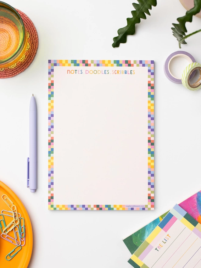 Raspberry Blossom doodle pad with multicoloured hand lettered ‘Notes.Doodles.Scribbles’ title on each page and a rainbow square tile border