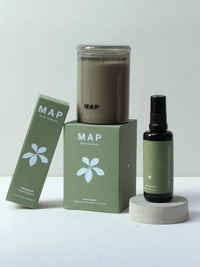 rest aromatherapy candle and home fragrance spray set. spray bottle and candle and boxes photographed against white studio backdrop.