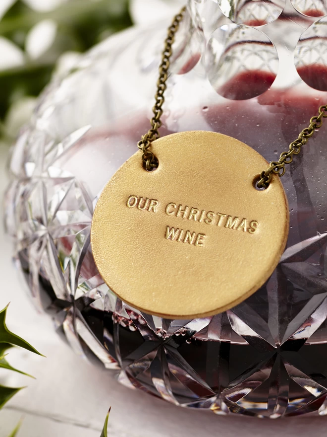 Gold Christmas bottle tag on a cut glass decanter bottle