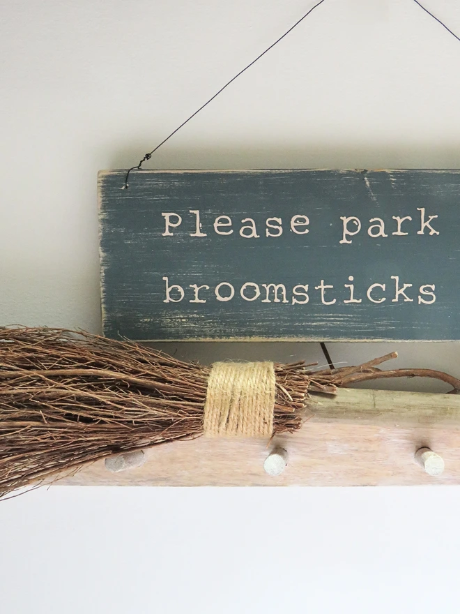 distressed hand painted wooden sign with broomstick parking message