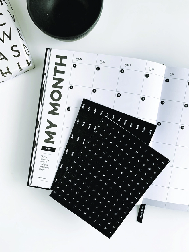 The Hello Time Planner open on a month to view page with date dots and month labels stickers laid on top