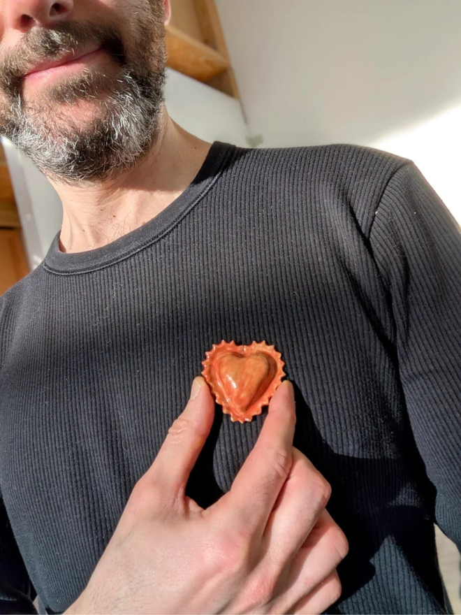 ceramic pasta pin badges. a ceramic heart-shaped ravioli badge photographed on a jumper.